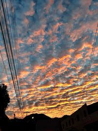 Low angle view of silhouette electricity pylon against sky during sunset