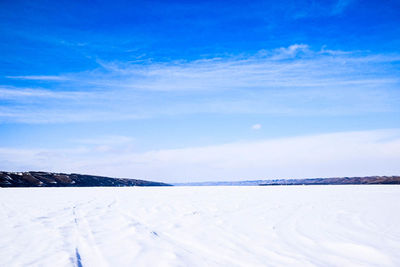 Scenic view of frozen landscape against blue sky