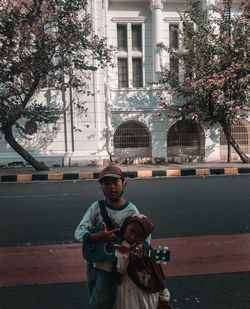 Portrait of young man standing against wall in city