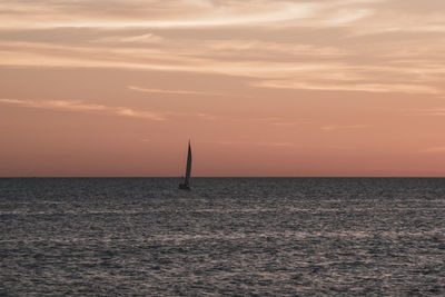 Sailboat on sea against sky during sunset