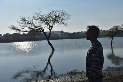 Man standing by lake against sky