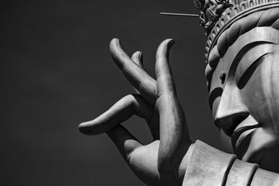 Close-up of a large, buddhist statue's hand against a black background.