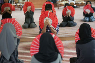 Dancers holding hand fans while sitting in studio