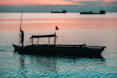 Silhouette boat in sea against sky during sunset