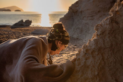 Side view of man on rock at beach