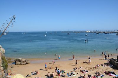 People on beach against clear blue sky