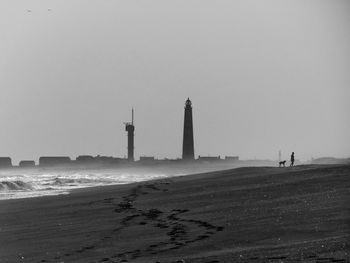 Lighthouse by sea against clear sky