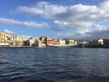 Sea by buildings against sky in city