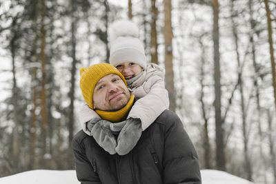 Smiling daughter embracing father in winter forest