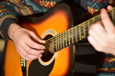 Playing acoustic guitar passionately close up photography