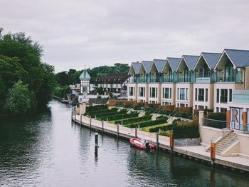 Buildings by river against sky