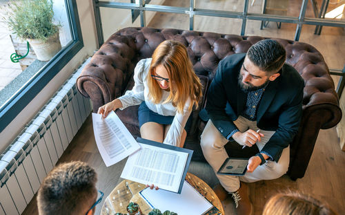 Top view of business people in an informal work meeting sitting on the couch