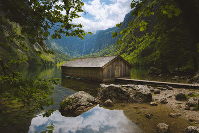 Reflection of shack in lake against sky