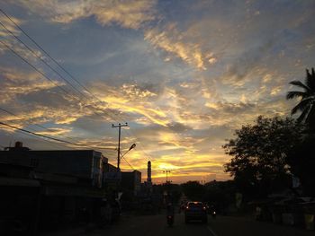 Cars on street against sky at sunset
