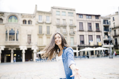 Close-up portrait of young woman against buildings in city