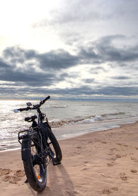 Bicycle on beach against sky