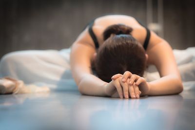 Ballet dancer stretching on floor