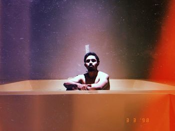 Digital composite of man with toy sitting in bathroom