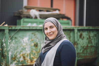 Portrait of smiling construction worker in headscarf at site