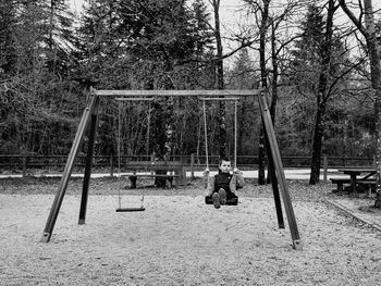 Man sitting on swing in park
