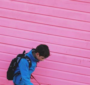 High angle view of boy standing by pink shutter