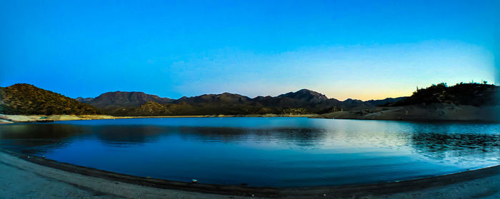 Scenic view of lake and mountains against clear blue sky