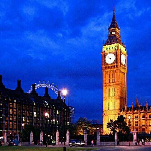 building exterior, architecture, built structure, sky, illuminated, city, blue, travel destinations, clock tower, famous place, tower, night, large group of people, tourism, low angle view, city life, travel, cloud - sky, capital cities