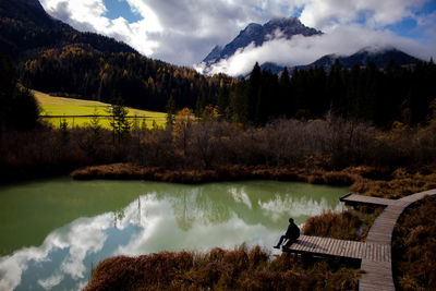 Young man sitting by lake during autumn