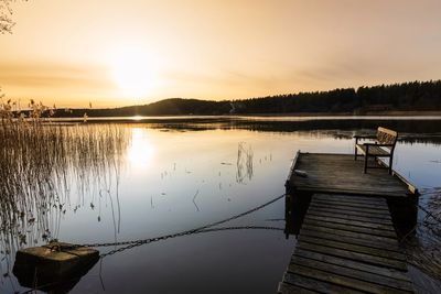 Pier on lake against sky during sunset