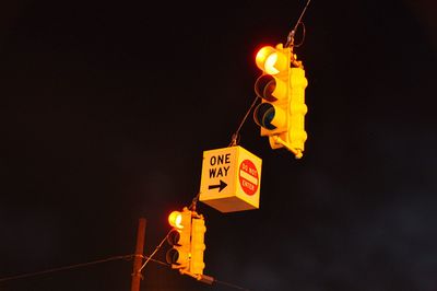 Low angle view of illuminated road sign at night