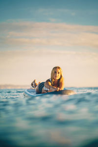 Portrait of woman relaxing in sea against sky