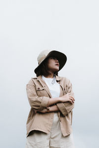 Low angle view of young woman wearing hat standing against sky