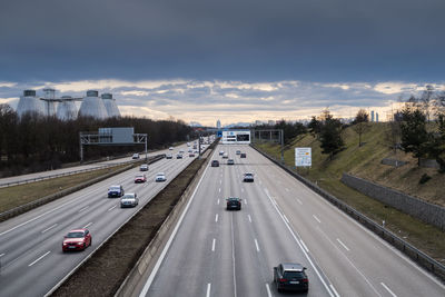 Vehicles on highway against sky in city