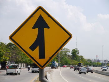 Road sign on street against sky