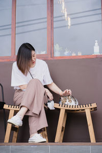 Asian woman sit and play with her cat at outdoor coffee shop