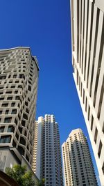Low angle view of modern buildings against clear blue sky