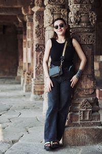 Portrait of young woman standing against building