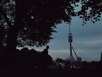 Silhouette of trees and tower against sky