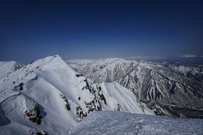 Scenic view of snowcapped mountains against clear blue sky