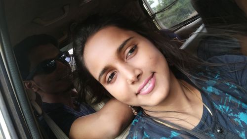 Close-up of smiling young woman traveling in vehicle