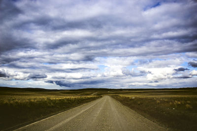 Country road along landscape against sky