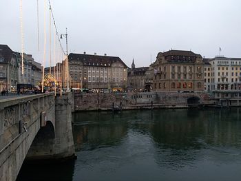 Bridge over canal by buildings against sky in city