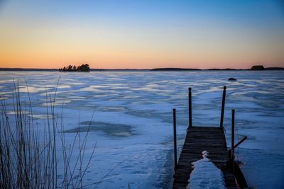 Pier on lake against sky during sunset
