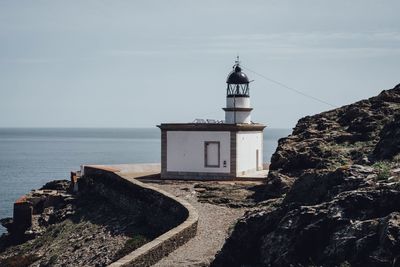 Lighthouse by sea against sky
