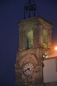Low angle view of clock tower against sky at night
