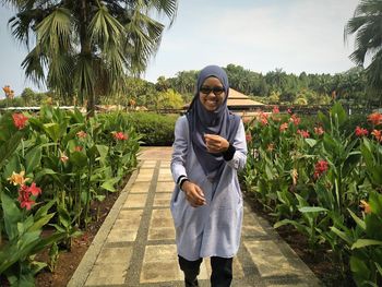 Portrait of smiling young woman standing against plants