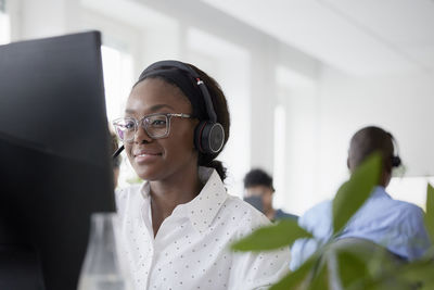 Mid adult woman using headset while sitting in office