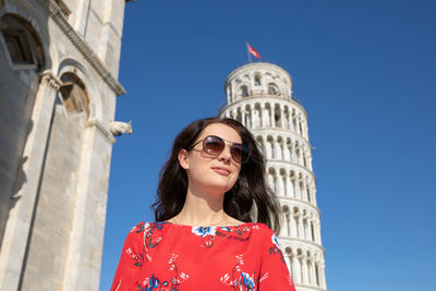 Woman wearing sunglasses while standing against leaning tower of pisa