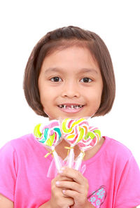 Portrait of smiling girl holding candies against white background