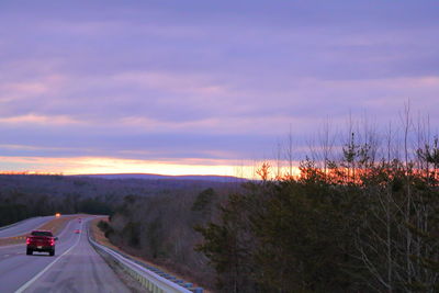 Cars on road against sky during sunset